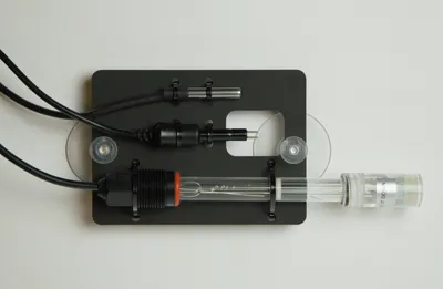 A mounting plate holding the pH sensor and water level sensor in place above the reservoir with suction cups.